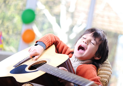 Kid singing and playing guitar at home